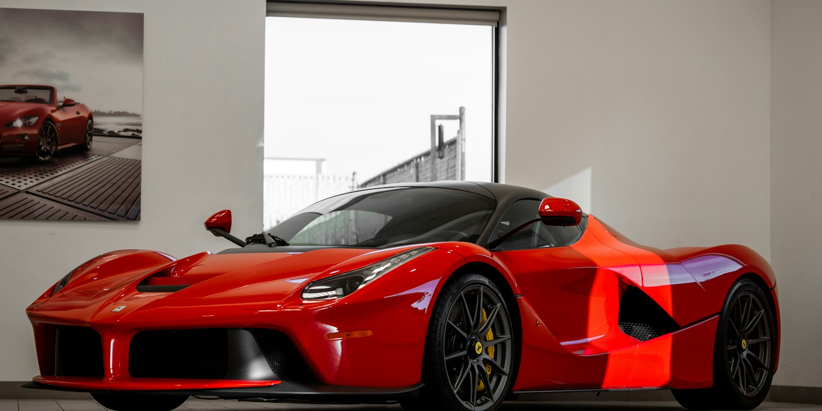 Red supercar in a bright white studio space.