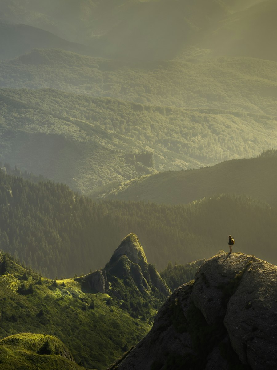 Mountain valley with a lone figure on a ridge.