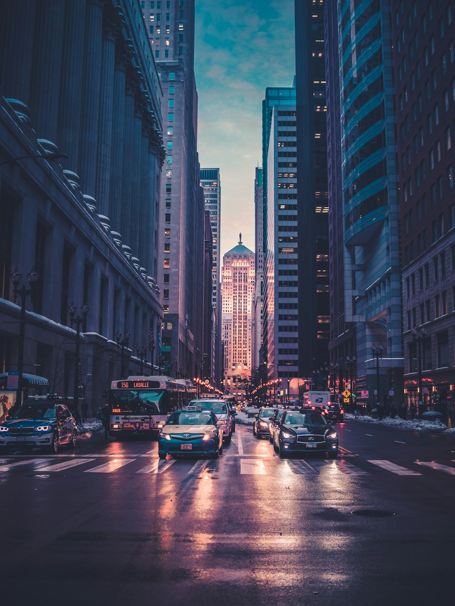City street at dusk with traffic and tall buildings.