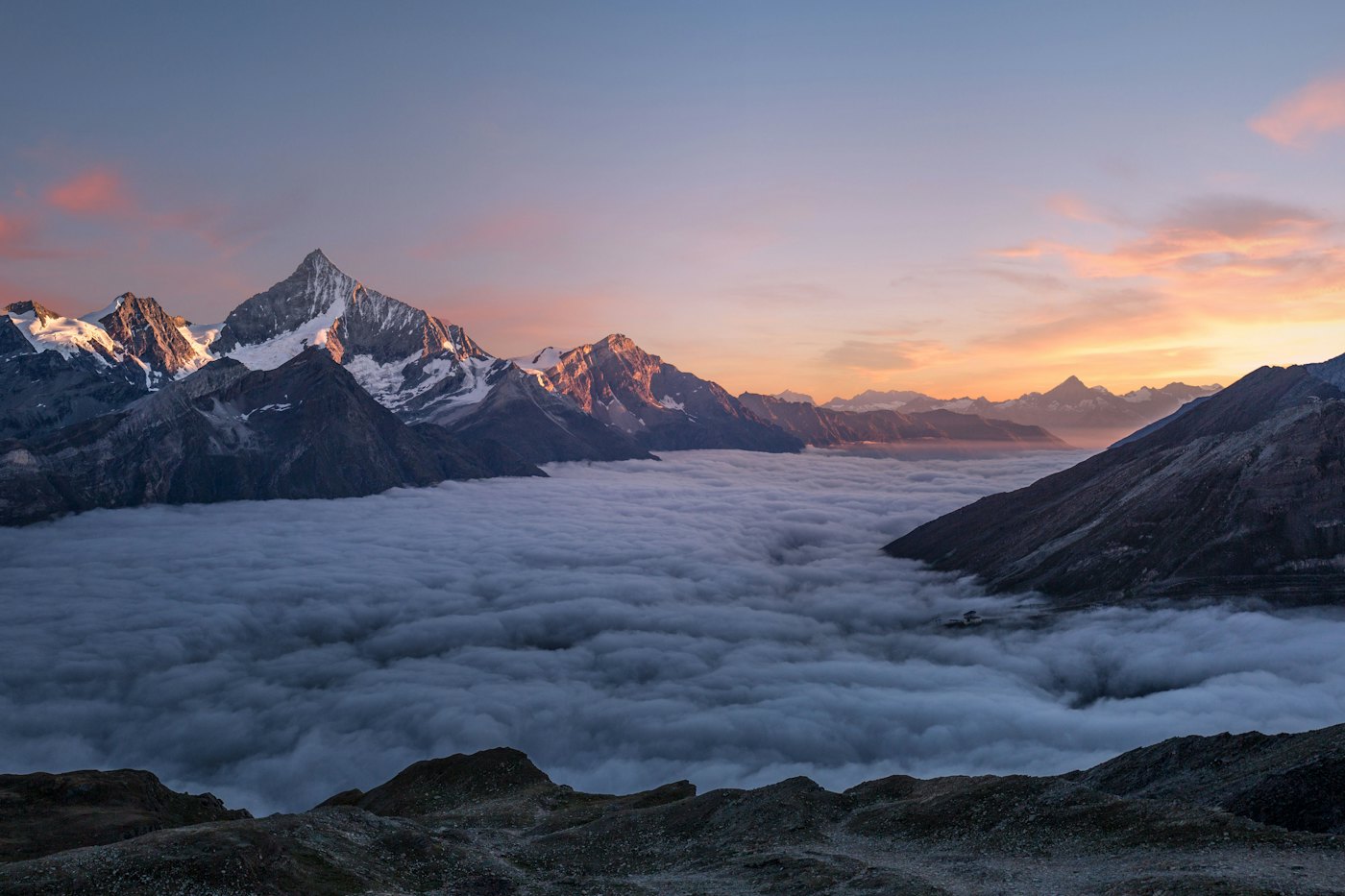 Mountain peaks above a sea of cloud at sunrise.