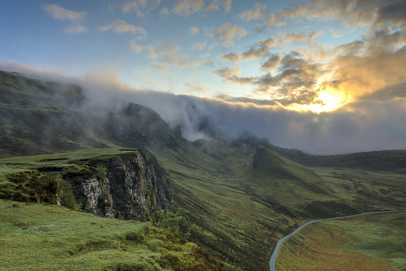 Green hills and a winding road under low cloud.
