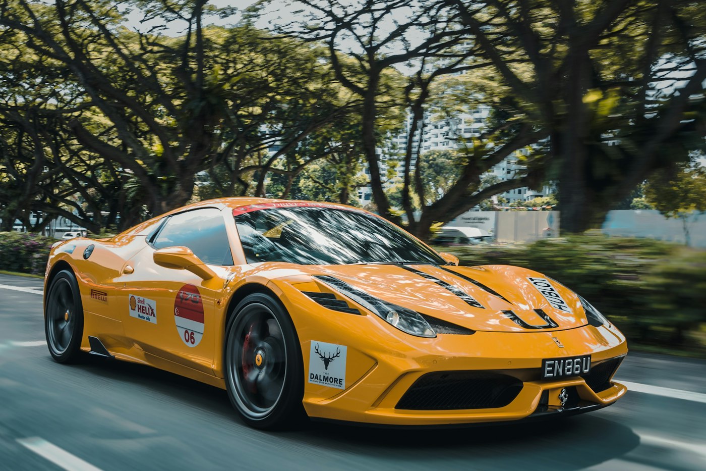 Yellow sports car panned at speed on a tree-lined road.