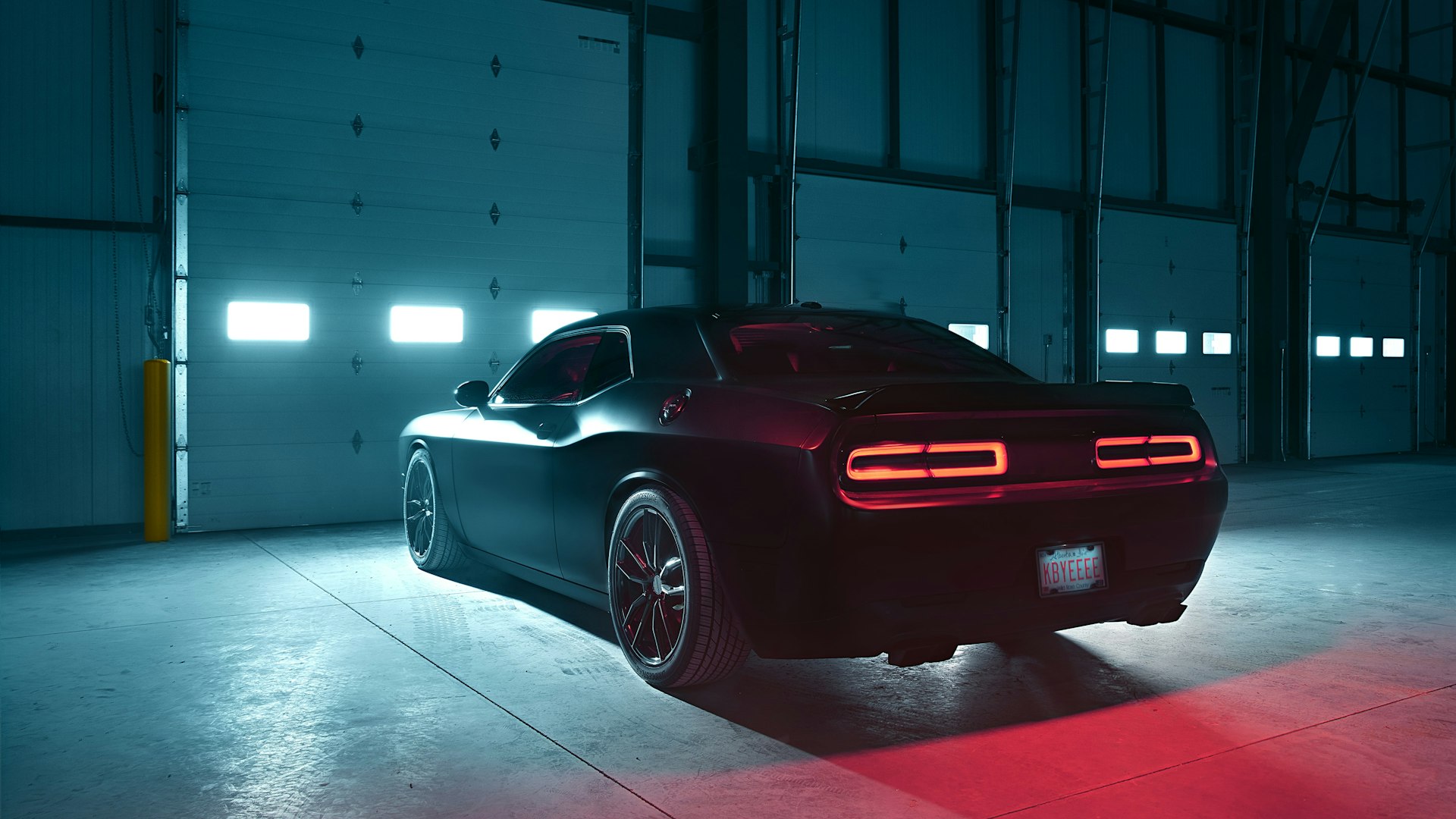 A dark muscle car in a moody, spot-lit garage.