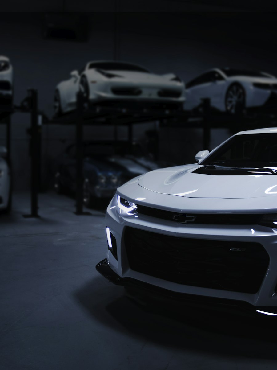 White muscle car lit in a dark collection garage.